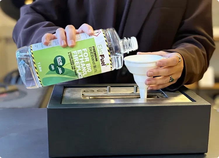 vertiendo combustible bioetanol en un quemador con un embudo de plástico